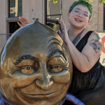 Moony, posing smiling and cozied up to a metal Humpty Dumpty (or man in the moon?) statue